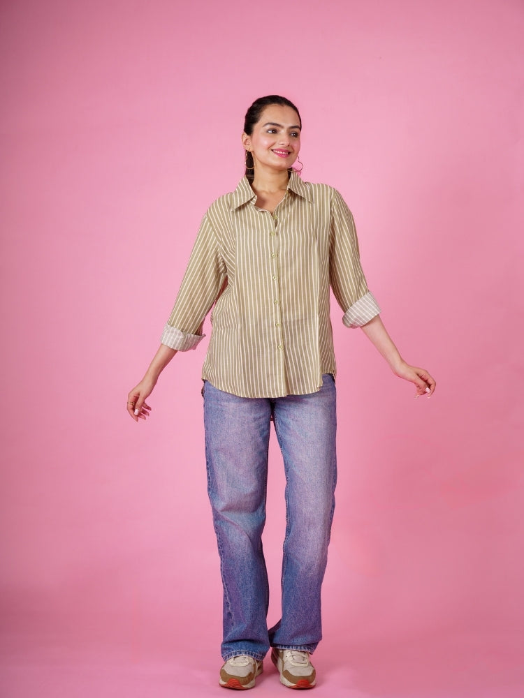 Woman wearing a ekisha mehandi striped shirt and jeans against a pink background, front view