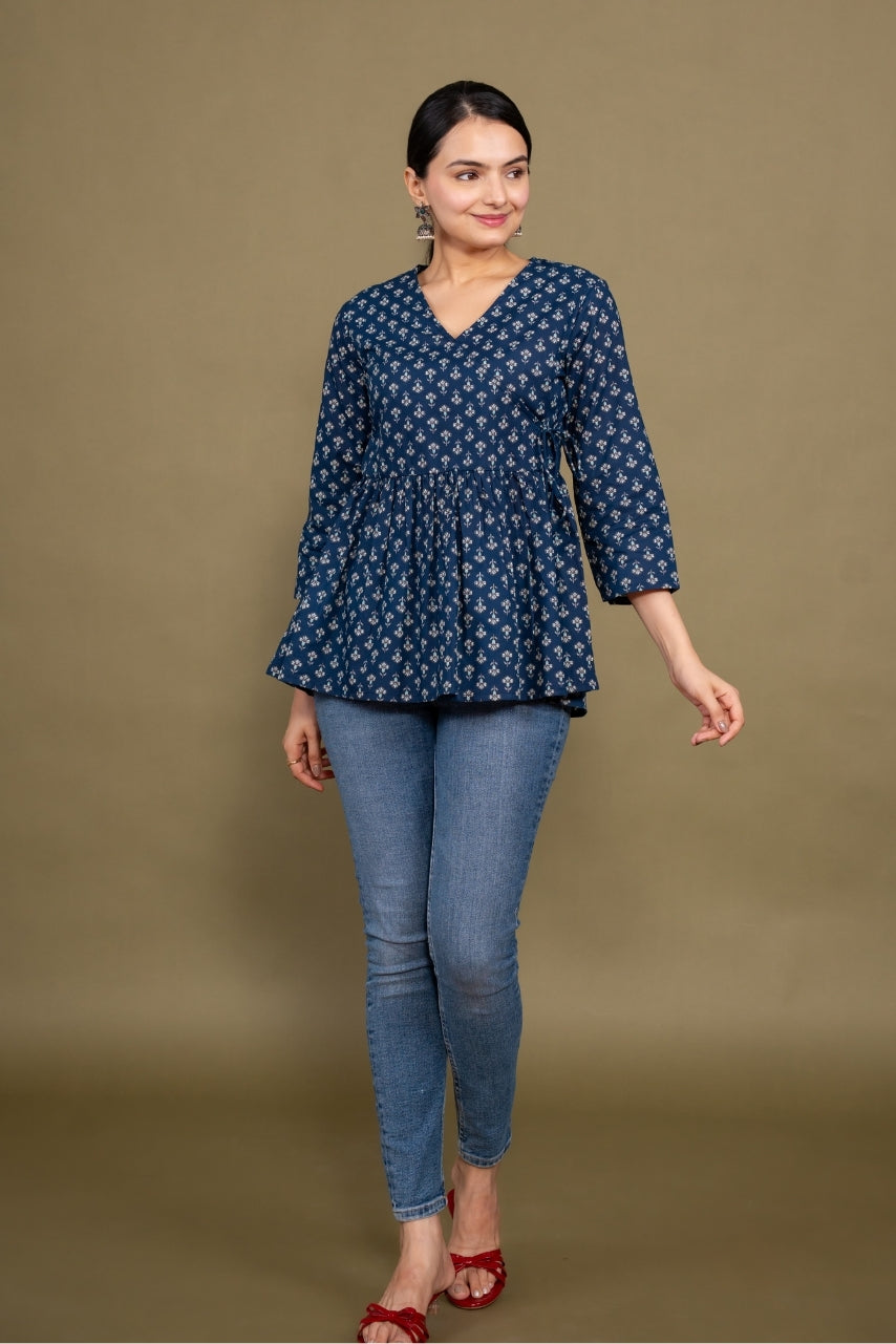 Woman wearing a blue patterned top and jeans against a brown background