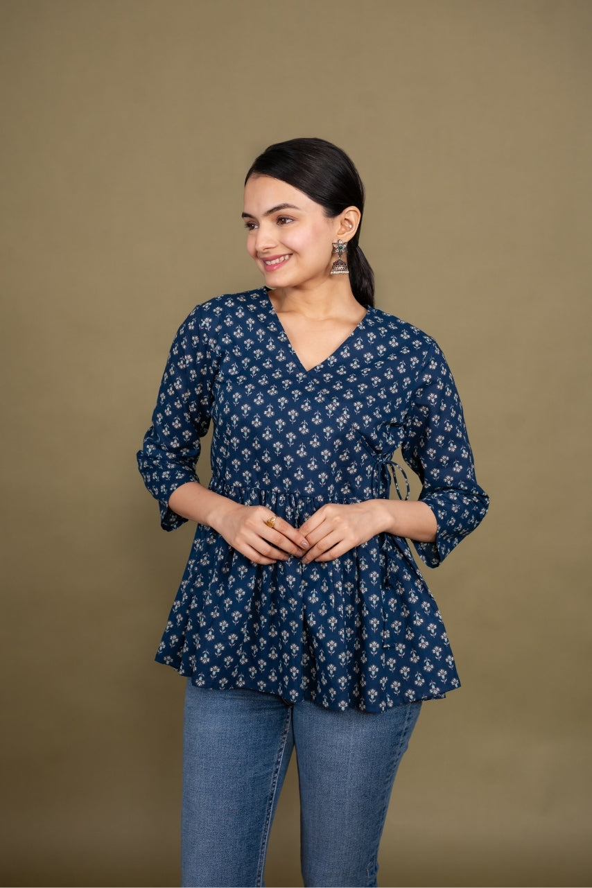 Woman wearing a blue patterned top and jeans against a brown background