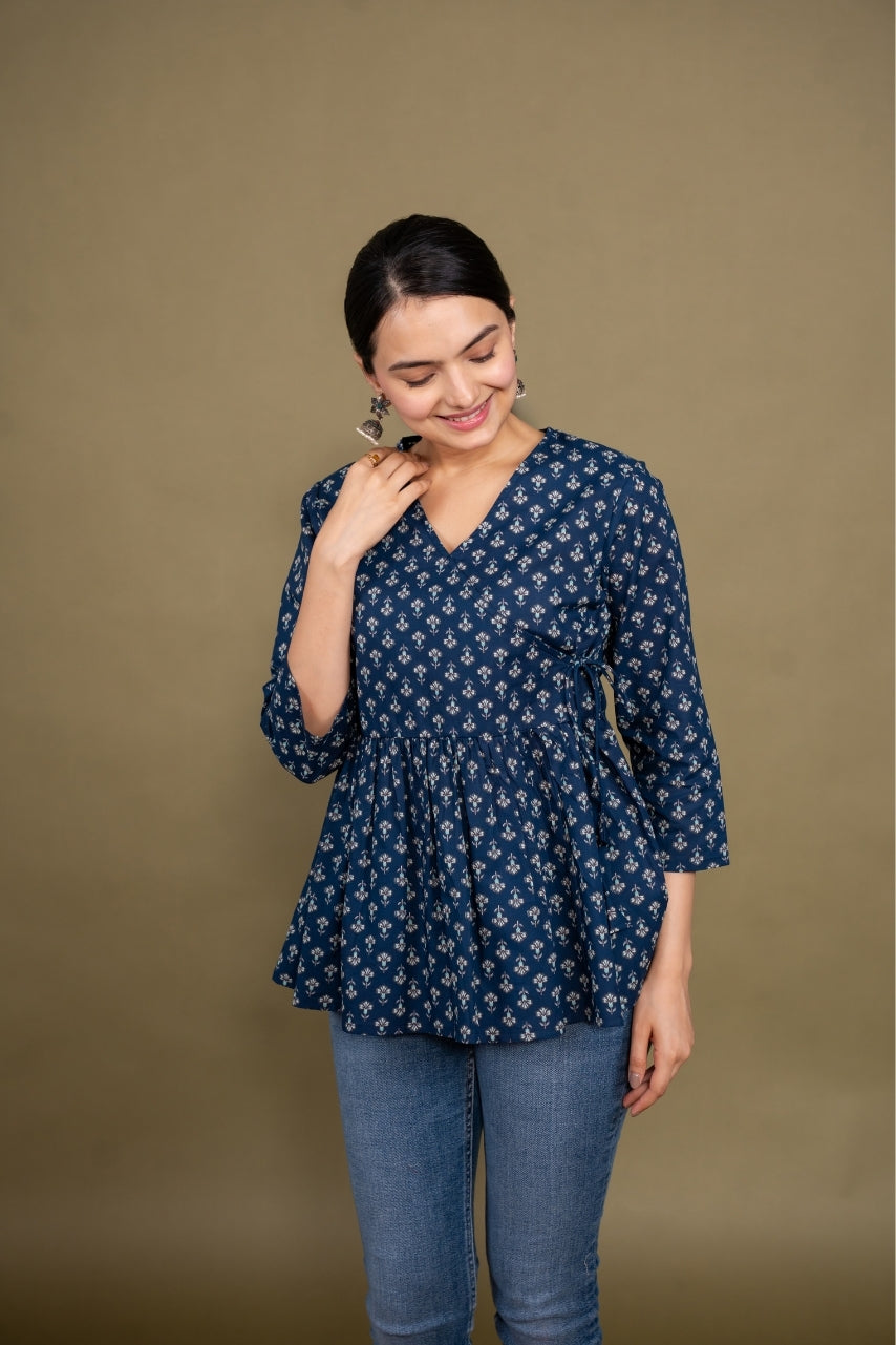 Woman wearing a blue patterned top and jeans against a brown background
