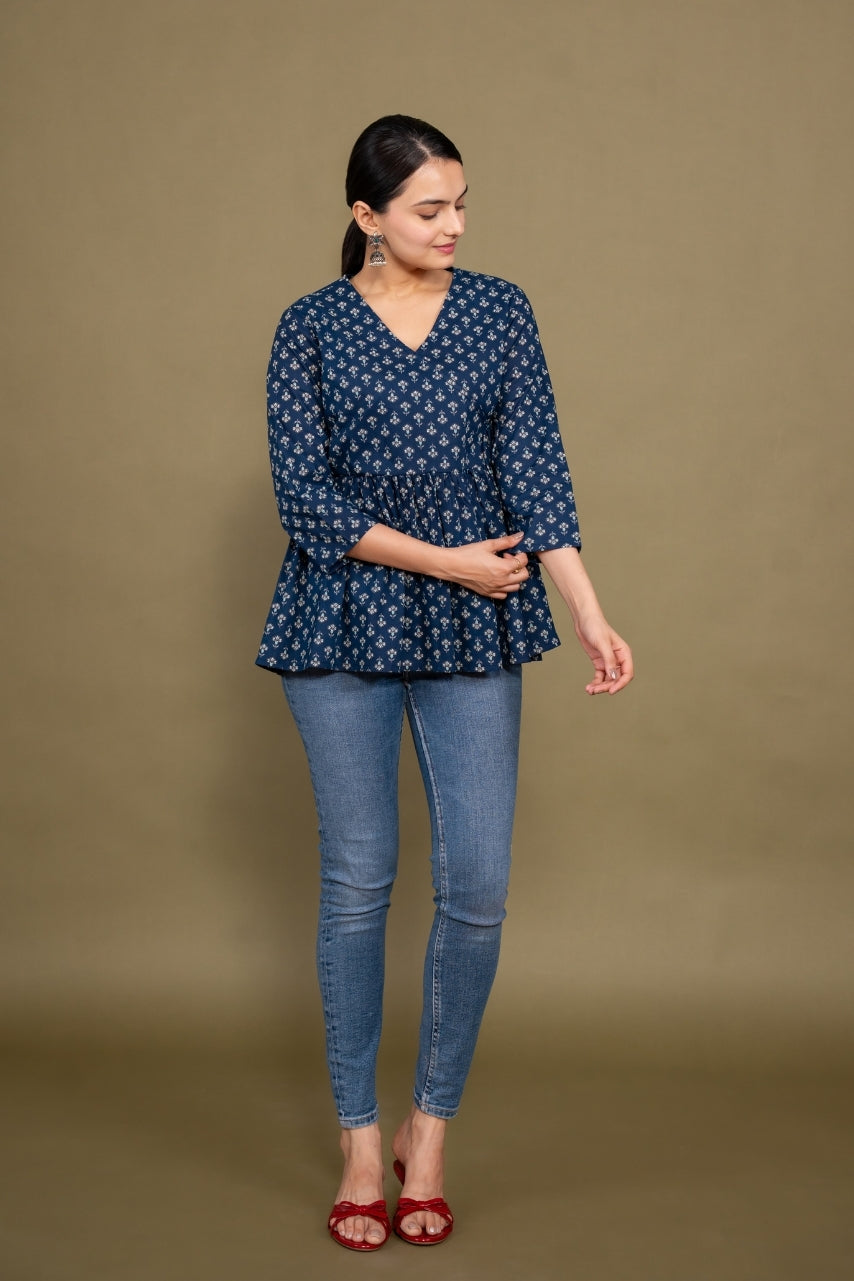 Woman wearing a blue patterned top and jeans on a brown background
