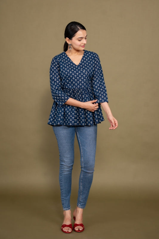 Woman wearing a blue patterned top and jeans on a brown background